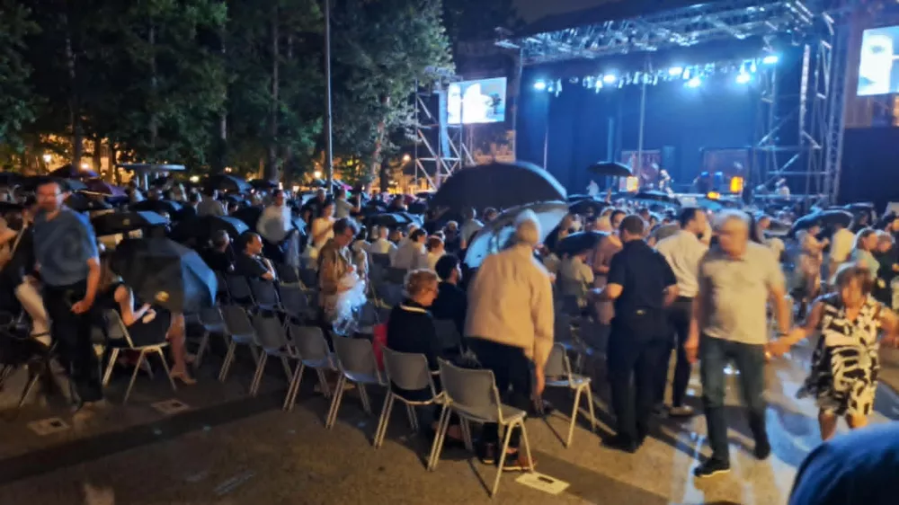 Trenutek, ko so obiskovalci slavnostnega odprtja 74. Ljubljana Festivala začeli vstajati, odpirati dežnike in zapu&scaron;čati prizori&scaron;če na prostem na Kongresnem trgu. F Alenka &Scaron;ubic