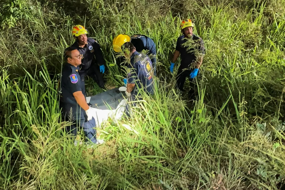 Rescue workers recover a suitcase from a grassy area near a railway track, in which police later found the body of a 17-year-old Thai girl, in Pattaya City, Thailand, June 27, 2026. Picture taken with a mobile phone. REUTERS/Teerasak Suttativong