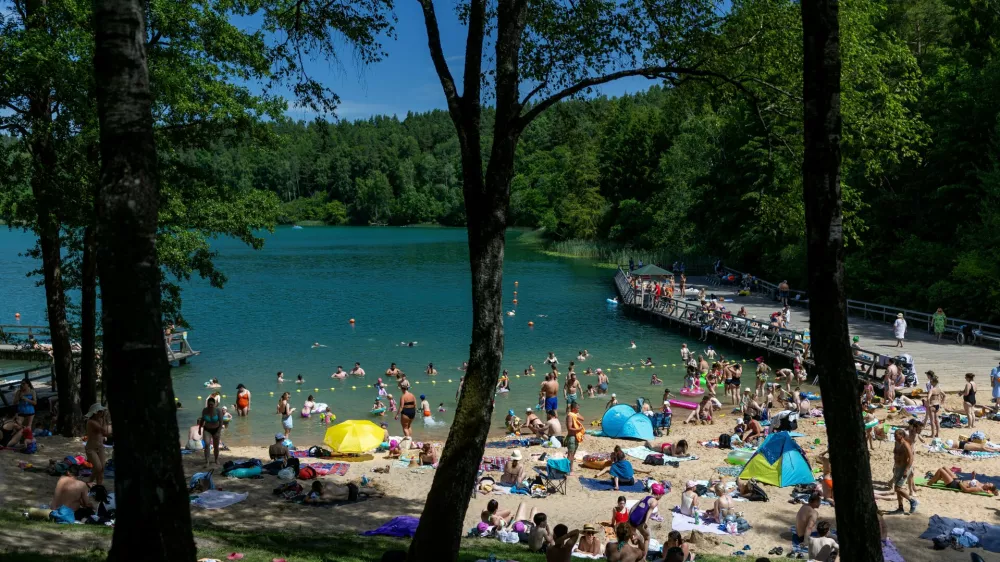People enjoy a warm weather by a lake near Vilnius, Lithuania, Saturday, June 27, 2026. (AP Photo/Mindaugas Kulbis)