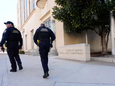 FILE - Officers with the Department of Homeland Security walk on the sidewalk outside the Eldon B. Mahon U.S. Courthouse during a trial for people connected to a 2025 shooting outside an ICE detention facility, in Fort Worth, Texas, March 12, 2026. (AP Photo/Tony Gutierrez, File)