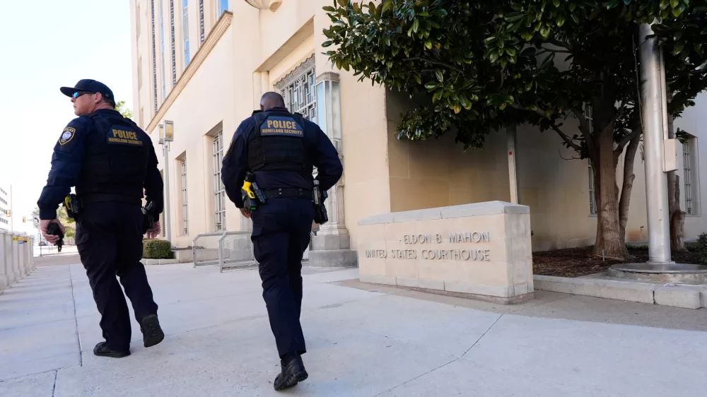 FILE - Officers with the Department of Homeland Security walk on the sidewalk outside the Eldon B. Mahon U.S. Courthouse during a trial for people connected to a 2025 shooting outside an ICE detention facility, in Fort Worth, Texas, March 12, 2026. (AP Photo/Tony Gutierrez, File)
