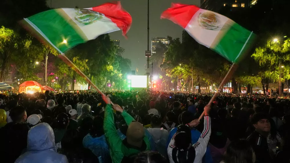 Mexican fans wave flags as they watch the World Cup round of 32 soccer match between Mexico and Ecuador near the Angel of Independence monument in Mexico City, Tuesday, June 30, 2026. (AP Photo/Marco Ugarte)