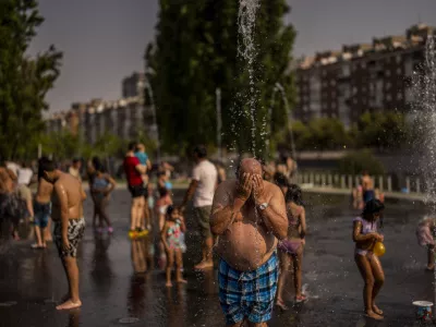 People cool off in an urban beach at Madrid Rio park in Madrid, Spain, Wednesday, July 13, 2022. Weather forecasters say Spain is expected to have its second heat wave in less than a month and that it will will last at least until the weekend. Meteorologists said an overheated mass of air and warm African winds are driving temperatures in the Iberian Peninsula beyond their usual highs. (AP Photo/Manu Fernandez)