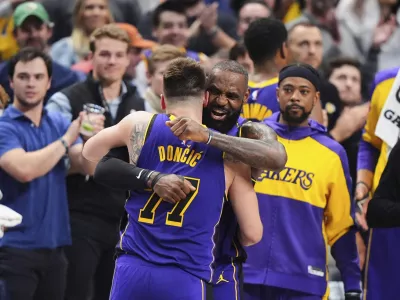 Los Angeles Lakers' Luka Doncic (77) and LeBron James, center, right, hug and celebrate late in the second half of an NBA basketball game against the Dallas Mavericks in Dallas, Wednesday, April 9, 2025. (AP Photo/LM Otero)