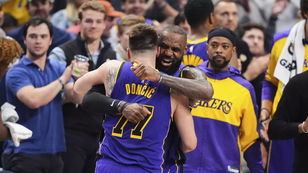 Los Angeles Lakers' Luka Doncic (77) and LeBron James, center, right, hug and celebrate late in the second half of an NBA basketball game against the Dallas Mavericks in Dallas, Wednesday, April 9, 2025. (AP Photo/LM Otero)