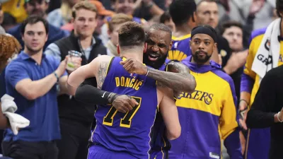 Los Angeles Lakers' Luka Doncic (77) and LeBron James, center, right, hug and celebrate late in the second half of an NBA basketball game against the Dallas Mavericks in Dallas, Wednesday, April 9, 2025. (AP Photo/LM Otero)