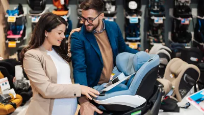 Beautiful couple choosing and buying car safety seat for their baby. Parenthood and child expecting concept.