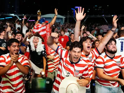 U.S. soccer fans, including Caleb Triana, center, and Nicolas Cerda, dressed as a founding father, celebrate the U.S. scoring its second goal, as they watch a live broadcast of the World Cup round of 32 soccer match between the United States and Bosnia, Wednesday, July 1, 2026, at an official fan fest in downtown Miami. (AP Photo/Rebecca Blackwell)