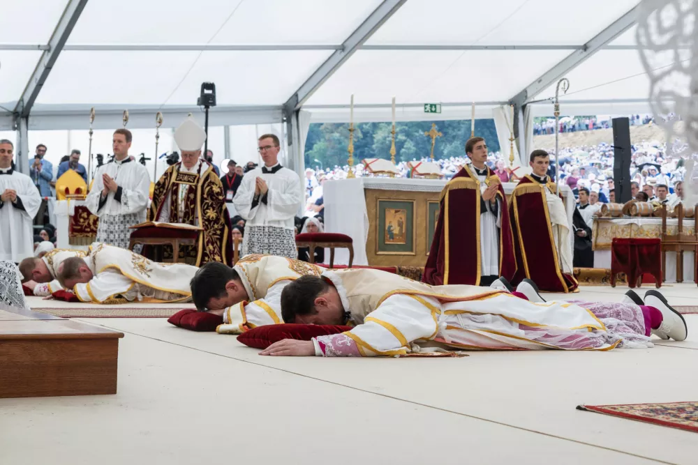 Four bishops lie on the floor as they are given episcopal consecration during a Mass in a tent set up outside the Society of St. Pius X seminary, in Econe, Switzerland, Wednesday, July 1, 2026. (Cyril Zingaro/Keystone via AP)