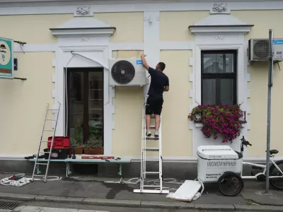 An installer sets a new air conditioning unit during a hot summer day in Belgrade, Serbia, Tuesday, June 30, 2026. (AP Photo/Darko Vojinovic)