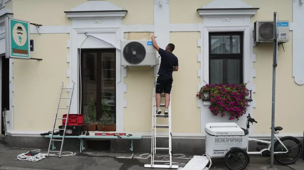 An installer sets a new air conditioning unit during a hot summer day in Belgrade, Serbia, Tuesday, June 30, 2026. (AP Photo/Darko Vojinovic)