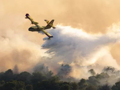 A firefighting plane sprays water to extinguish wildfire at Ciovo island, Croatia, Thursday, July 27, 2023. A large fire is reported on the island of Ciovo, close to Split on the Croatian Adriatic coast. (AP Photo/Miroslav Lelas)