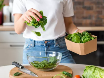 Close up woman in white t-shirt cooking salad with motion effect at home kitchen. Process of cooking healthy food, vegetable concept