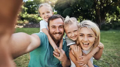 Nature, selfie and portrait of a happy family on a picnic together in outdoor green garden. Happy, smile and parents playing, hugging and bonding with children outside in backyard or park in canada.