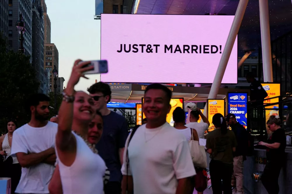 People take selfies next to a screen displaying a message referencing singer Taylor Swift and National Football League (NFL) player Travis Kelce outside Madison Square Garden, the venue for their wedding celebrations, in New York, U.S., July 3, 2026. REUTERS/Angelina Katsanis   TPX IMAGES OF THE DAY