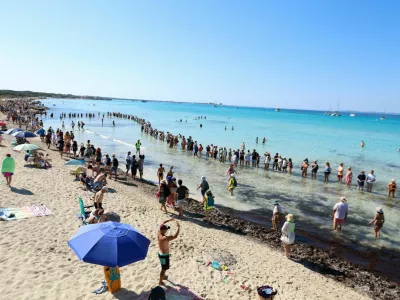 Activists and residents form a human chain on a beach to protest overtourism and call for stronger protection of the island's natural coastal areas, in La Rapita, Mallorca, Spain, July 5, 2026. REUTERS/Francisco Ubilla