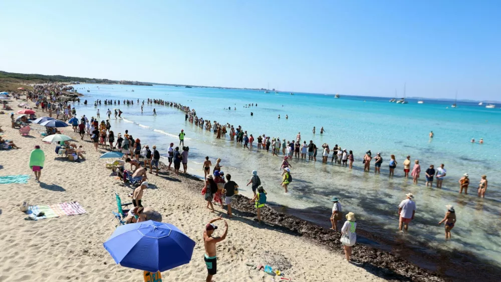 Activists and residents form a human chain on a beach to protest overtourism and call for stronger protection of the island's natural coastal areas, in La Rapita, Mallorca, Spain, July 5, 2026. REUTERS/Francisco Ubilla