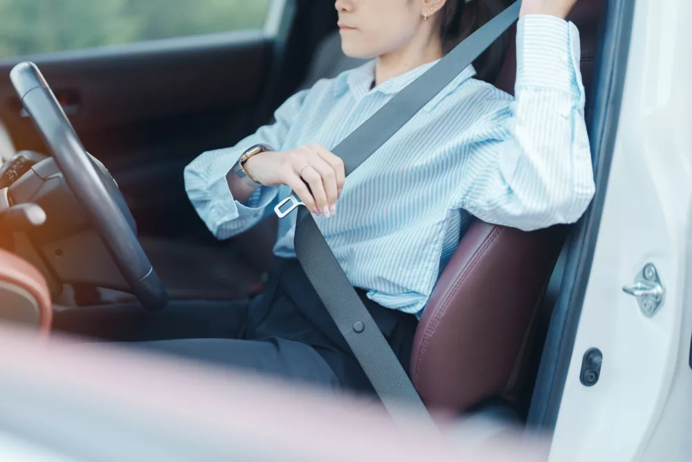 Business woman driver hand fastening seat belt during sitting inside a car and driving in the road. safety, trip, journey and transport concept