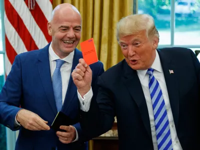 FILE - President Donald Trump holds up a red card during a meeting with FIFA president Gianni Infantino in the Oval Office of the White House, Tuesday, Aug. 28, 2018, in Washington. (AP Photo/Evan Vucci, File)