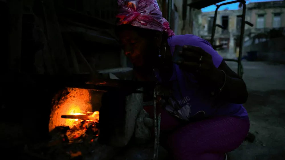 Odalys Ramos, 62, lights firewood to prepare coffee in front of her home as Cuba's national electric grid collapsed at midday, leaving around 10 million people without power, in Havana, Cuba, July 6, 2026. REUTERS/Norlys Perez