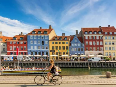 Copenhagen, Denmark - July, 2019: Copenhagen iconic view. Famous old Nyhavn port with colorful medieval houses, tourist ship and woman on a bicycle in the center of Copenhagen. Selective focus.