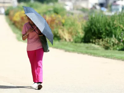 A person uses an umbrella to shield from the sun whilst walking along the River Thames, as Britain experiences record temperatures disrupting schools and transport networks, at Richmond, in London, Britain, June 25, 2026. REUTERS/Toby Melville