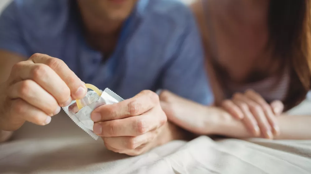 Close-up of couple with a condom on bed in the bedroom
