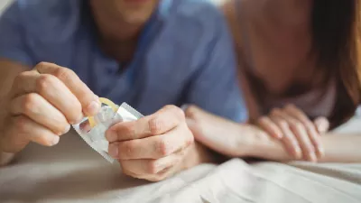 Close-up of couple with a condom on bed in the bedroom