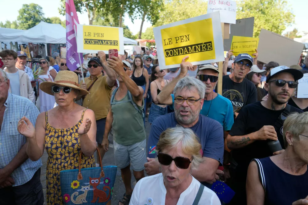 Protestor hold placards reading: Le Pen convicted, during a protest against the visit of far-right leader Marine Le Pen in La Fleche, western France, Wednesday, July 8, 2026. (AP Photo/Michel Euler)