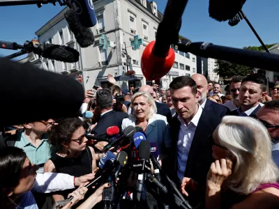 French far-right leader Marine Le Pen and Jordan Bardella, president of the French far-right Rassemblement National (National Rally - RN) political party, talk to journalists as they arrive to visit a market in La Fleche, in the Sarthe department, a day after Le Pen announced her candidacy for the 2027 French presidential election following an appeals court ruling that shortened her ban on running for office while upholding her conviction for embezzling EU funds, France, July 8, 2026. REUTERS/Benoit Tessier  TPX IMAGES OF THE DAY