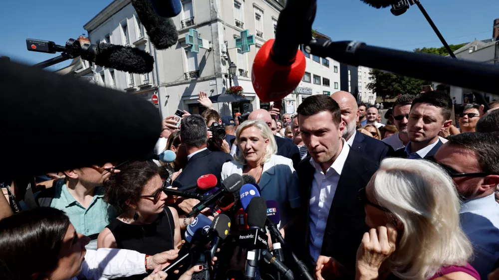 French far-right leader Marine Le Pen and Jordan Bardella, president of the French far-right Rassemblement National (National Rally - RN) political party, talk to journalists as they arrive to visit a market in La Fleche, in the Sarthe department, a day after Le Pen announced her candidacy for the 2027 French presidential election following an appeals court ruling that shortened her ban on running for office while upholding her conviction for embezzling EU funds, France, July 8, 2026. REUTERS/Benoit Tessier  TPX IMAGES OF THE DAY