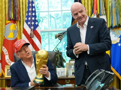 FILE - President Donald Trump holds the FIFA World Cup Winners Trophy as FIFA President Gianni Infantino looks on during an announcement in the Oval Office of the White House, Aug. 22, 2025, in Washington. (AP Photo/Jacquelyn Martin, File)