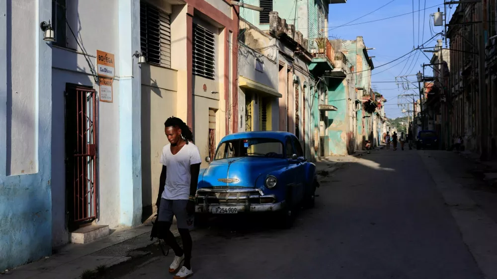 A man walks past a vintage car ahead of an announcement by Cuba's grid operator UNE that it had reconnected most of the country to the national grid, though millions remained without power as the country struggles to generate even one-third of current demand amid an ongoing U.S. fuel blockade, in Havana, Cuba, July 7, 2026. REUTERS/Norlys Perez