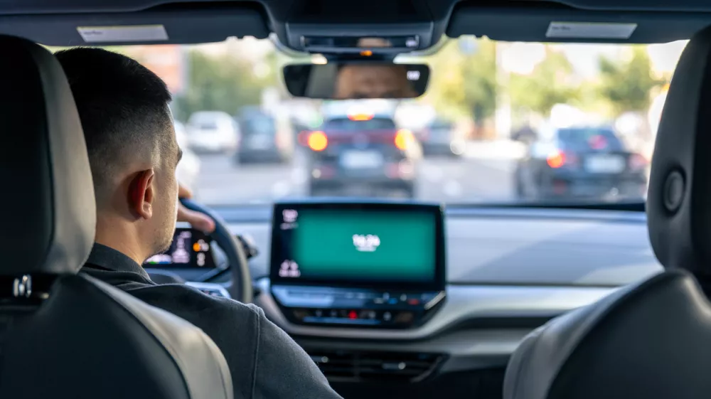 A male driver drives at speed through the streets of the city, a view from inside the car.