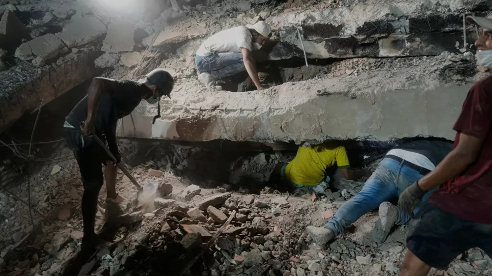 The family Nunez search for a relative in the debris of collapsed building by the earthquakes in La Guaira, Venezuela, Thursday, July 9, 2026. (AP Photo/Ariana Cubillos)