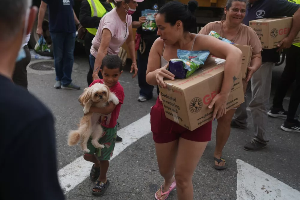 People affected by the earthquakes carry U.S. humanitarian aid after receiving it in La Guaira, Venezuela, Thursday, July 9, 2026. (AP Photo/Ariana Cubillos)