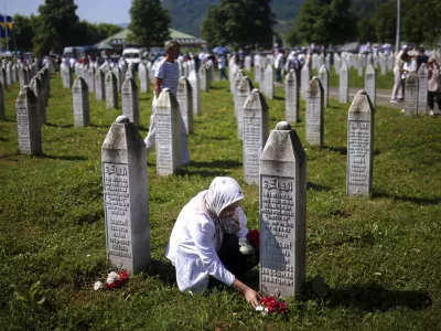 A Bosnian muslim woman lays flowers at the grave of her relative, victim of the Srebrenica genocide, at the Srebrenica Memorial Centre, in Potocari, Bosnia, Thursday, July 11, 2024. Thousands gather in the eastern Bosnian town of Srebrenica to commemorate the 29th anniversary on Monday of Europe's only acknowledged genocide since World War II. (AP Photo/Armin Durgut)