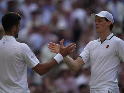 Novak Djokovic of Serbia, left, and Jannik Sinner of Italy greet each other at the end of their men's singles semifinal match at the Wimbledon Tennis Championships in London, Friday, July 10, 2026. (AP Photo/Brian Inganga)
