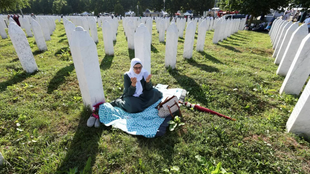 A Bosnian woman prays near the grave stones of victims during a memorial ceremony and funeral for ten victims, marking the 31st anniversary of the Srebrenica genocide in Potocari, Bosnia and Herzegovina, July 11, 2026. REUTERS/Amel Emric