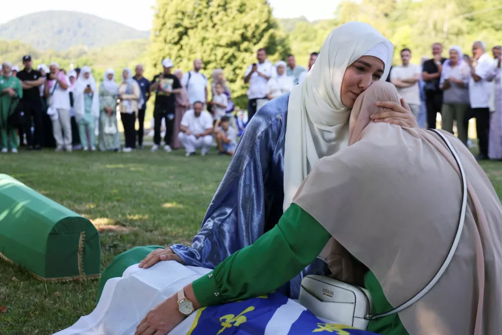 Bosnian woman Samedina Alihodzic comforts her mother Samira Guster near the coffin of her father Ahmet Guster, one of the ten victims whose funeral was held during a memorial ceremony, marking the 31st anniversary of the Srebrenica genocide in Potocari, Bosnia and Herzegovina, July 11, 2026. REUTERS/Amel Emric   TPX IMAGES OF THE DAY