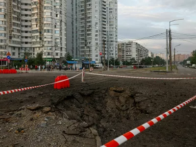 Residents gather next to a crater that appeared after Russian missile strikes, amid Russia's attack on Ukraine, in Kyiv, Ukraine July 11, 2026. REUTERS/Valentyn Ogirenko