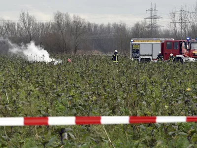 Firefighters stand at the area of a plane and helicopter crash near Philippsburg, Germany, Monday, Jan. 23, 2018. German police say a small aircraft has crashed midair with a helicopter northwest of Stuttgart. Police in Karlsruhe told the dpa news agency Tuesday the two aircraft crashed outside of Philippsburg, about 100 kilometers (60 miles) from Stuttgart. (Rene Priebe/dpa via AP)