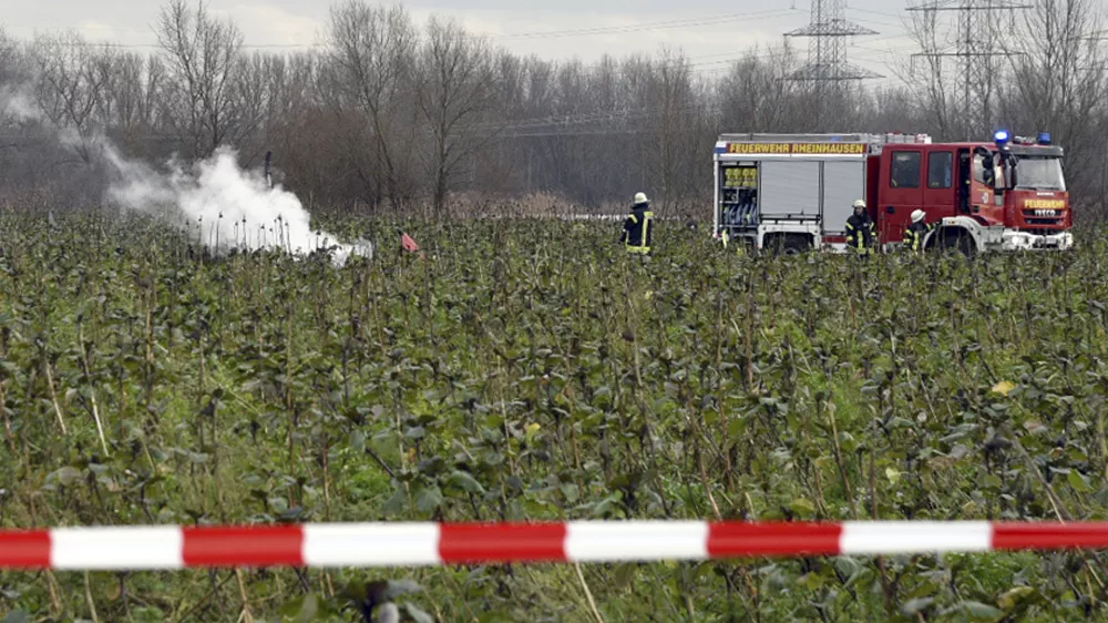 Firefighters stand at the area of a plane and helicopter crash near Philippsburg, Germany, Monday, Jan. 23, 2018. German police say a small aircraft has crashed midair with a helicopter northwest of Stuttgart. Police in Karlsruhe told the dpa news agency Tuesday the two aircraft crashed outside of Philippsburg, about 100 kilometers (60 miles) from Stuttgart. (Rene Priebe/dpa via AP)