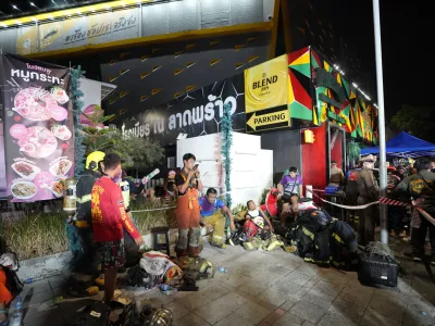 Rescuers rest after putting out a fire in Bangkok, Thailand, Monday, July 13, 2026. (AP Photo/Sakchai Lalit)