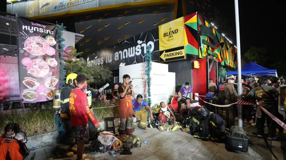 Rescuers rest after putting out a fire in Bangkok, Thailand, Monday, July 13, 2026. (AP Photo/Sakchai Lalit)