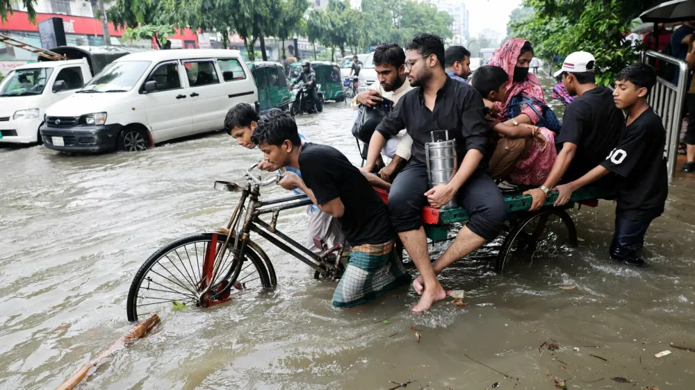 People cross a flooded street on tricycle following torrential rain in Dhaka, Bangladesh, July 12, 2026. REUTERS/Mohammad Ponir Hossain   TPX IMAGES OF THE DAY