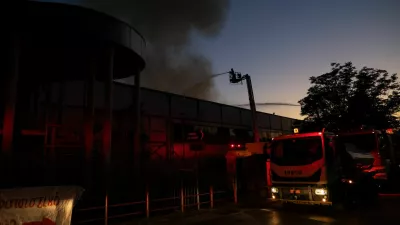 Firefighters spray water from aerial platforms as smoke rises from the roof of the Badminton Theater following a fire, in Athens, Greece, July 12, 2026. REUTERS/Stelios Misinas