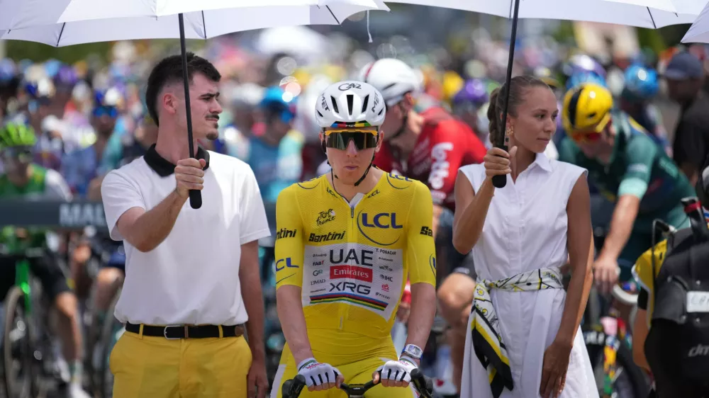 Slovenia's Tadej Pogacar, wearing the overall leader's yellow jersey, is shielded from the sun ahead of the start of the ninth stage of the Tour de France cycling race with start in Malemort and finish in Ussel, France, Sunday, July 12, 2026. (AP Photo/Mosa'ab Elshamy)
