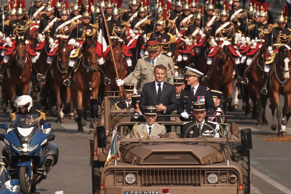 French President Emmanuel Macron, center, and General Chief of Staff of the French armed Forces Fabien Mandon stand in the command car as they review troops during the Bastille Day military parade on the Champs-Elysees avenue in Paris, Tuesday, July 14, 2026. (AP Photo/Thomas Padilla)