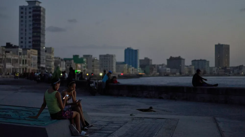 People hang out on the Malecon seawall at dusk during a blackout in Havana, Cuba, Tuesday, July 14, 2026 (AP Photo/Ramon Espinosa)